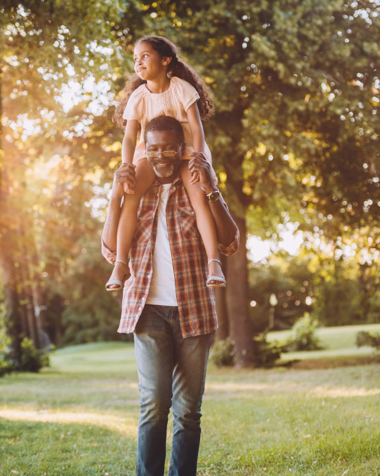 grandfather walking with granddaughter on his shoulders